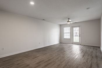 the living room of an empty house with white walls and a ceiling fan at Latitudes Apartments, Indiana